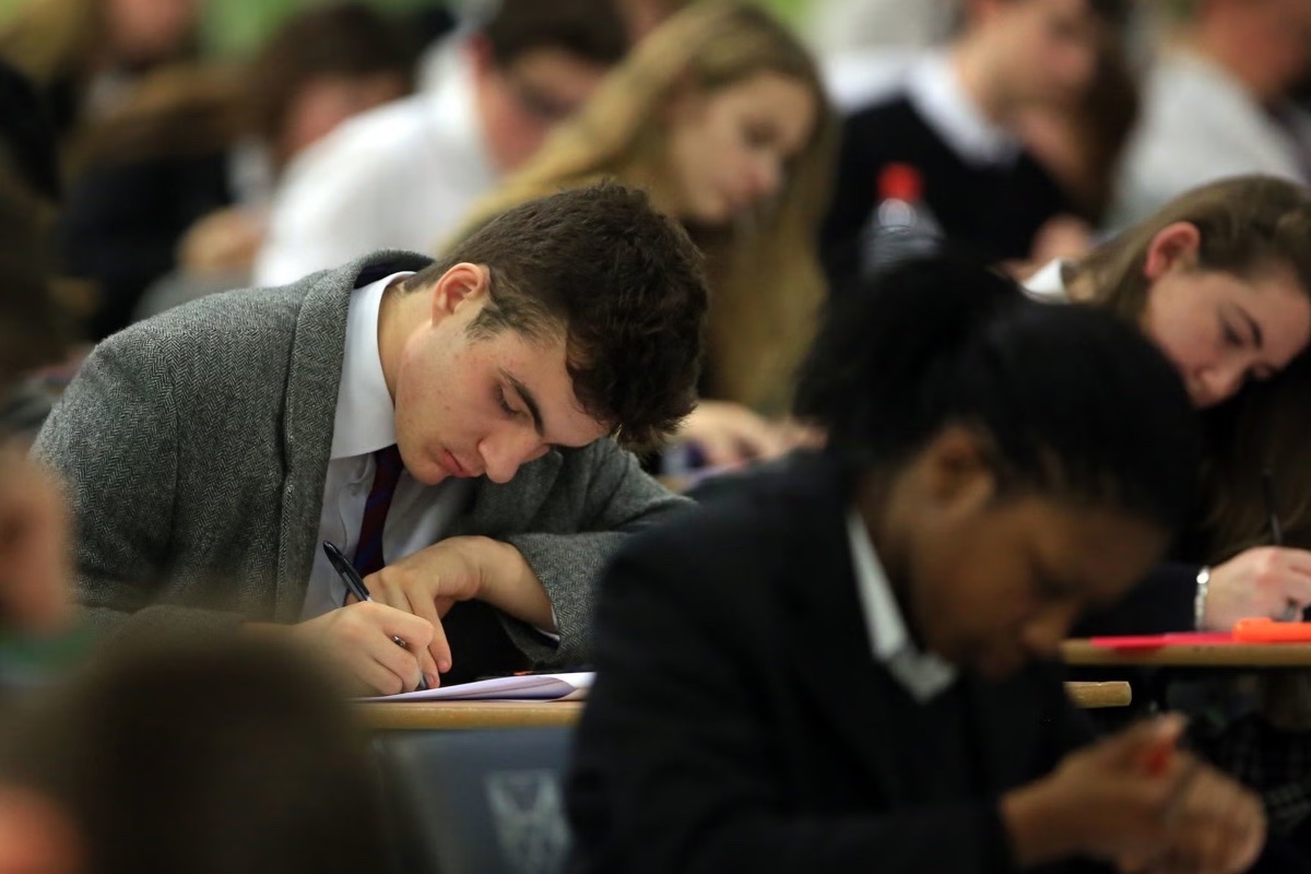 GCSE students completing written work in an exam room
