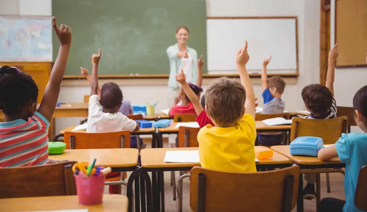 Primary school pupils raising their hands in a classroom